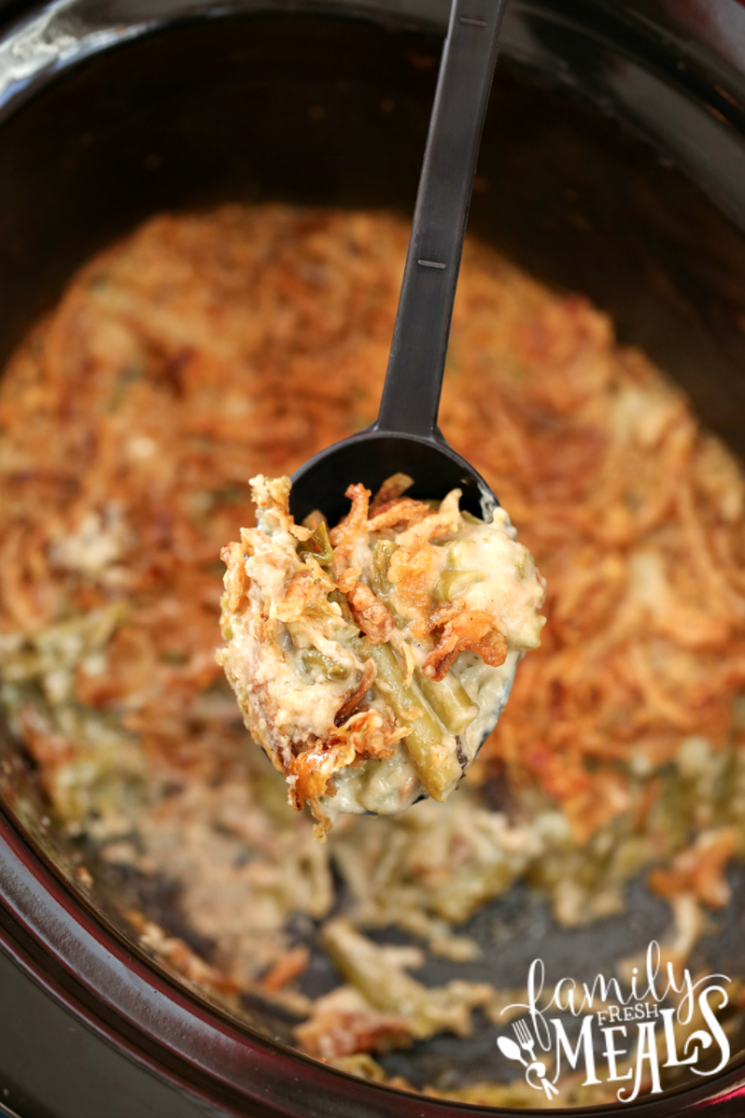 Spoon scooping up green bean casserole out of a slow cooker