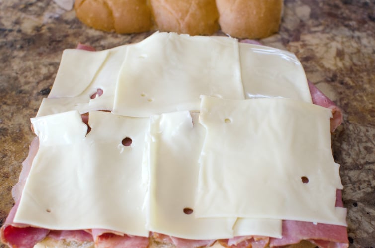 How to make Reuben Sliders - Slices of swiss cheese placed on top of deli slices
