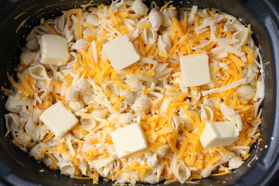 The Best Creamy Crockpot Mac and Cheese - butter tabs added to the top of shredded cheese