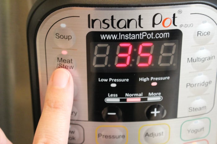 The Best Instant pot beef stew - finger pushing Meat/Stew button on Instant Pot pressure cooker