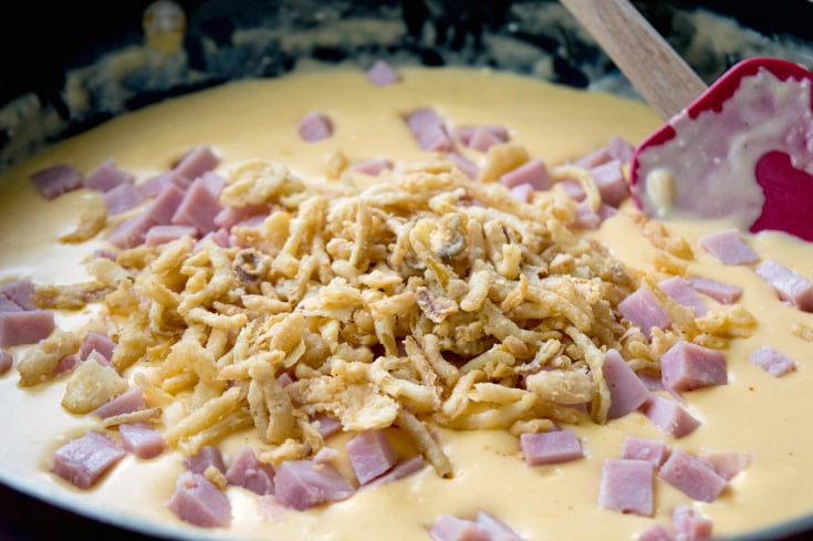Cheesy Ham Green Bean Casserole - mixing in fried onions, and cubed ham