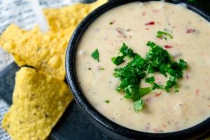 Crockpot White Queso Dip - Dip served in a dip bowl, topped with chilantro