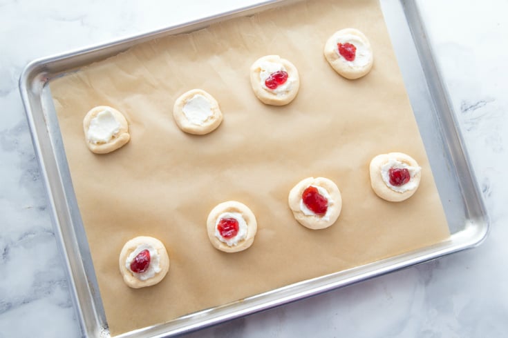 Cherry Cream Cheese Danish - Dough topped with cream cheese and cherry filling, on a baking sheet
