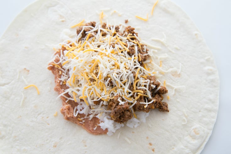 One Pan Smothered Beef Burrito Skillet - Tortilla topped with beans, rice cheese and beef