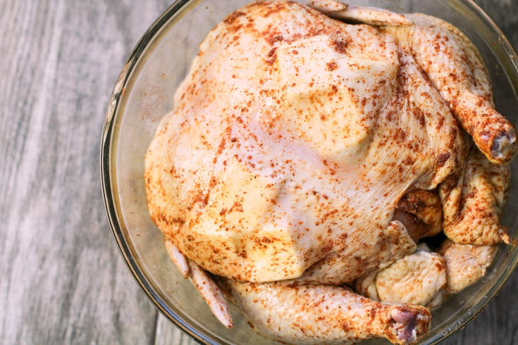 Instant Pot Beer Can Chicken - Whole raw chicken with seasoning rubbed on the outside, sitting in a glass bowl