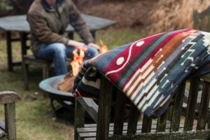 Ecuadane Ecuador Blanket draped over a wooden chair by a campfire