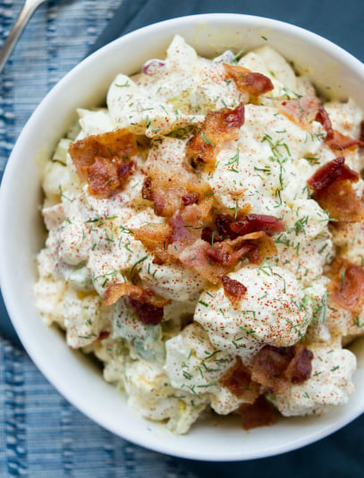 Cauliflower Potato Salad - served in a white bowl and topped with bacon