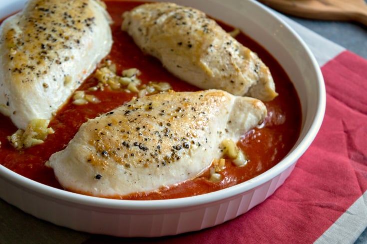 Pizza Chicken Bake - Browned chicken in a baking dish with red sauce