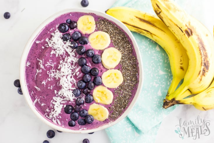 Blueberry Muffin Smoothie Bowl - Smoothie served in a white bowl topping with coconut, blueberries, bananas and chia seeds