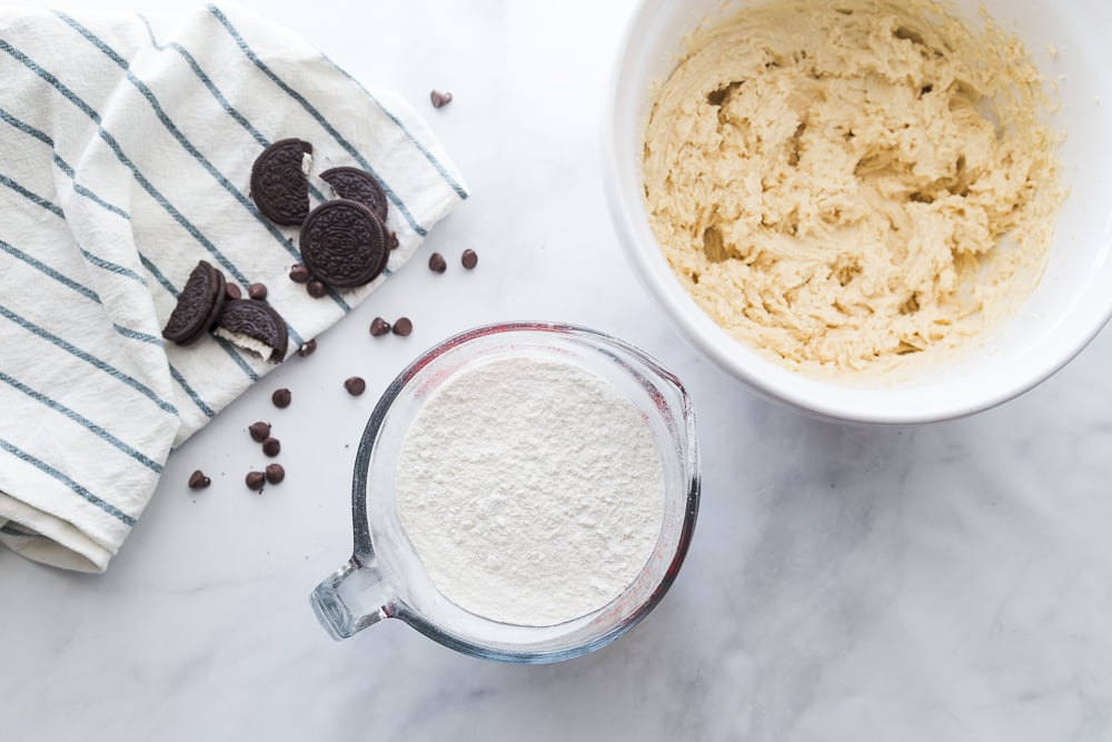 Jumbo Oreo Stuffed Chocolate Chip Cookies - Flour in a measuring cup and cookie batter in a white bowl