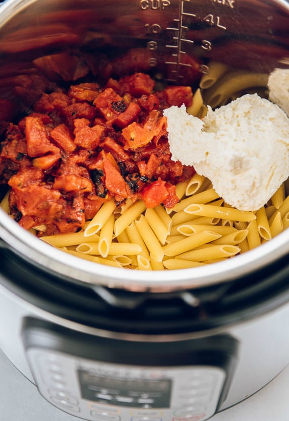 Instant Pot Three Cheese Ziti - tomatoes and cheese in instant pot with uncooked noodles