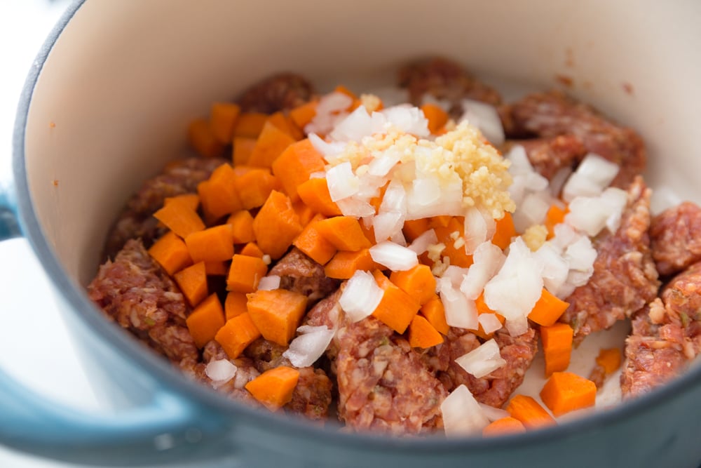 Italian Tortellini Soup Recipe - Sausage, carrots, onion and garlic cooking in dutch oven