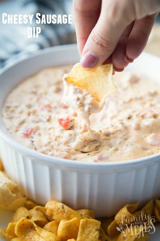 Cheesy Sausage Dip  in a white bowl surrounded by chips