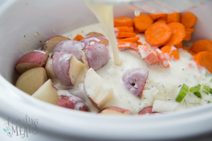 Creamy Crockpot Chicken Vegetable Soup - Pouring creamy mixture over chicken and vegetables