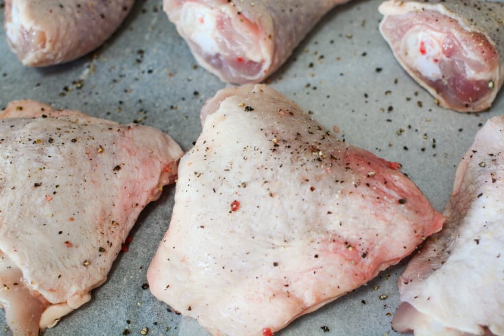 Baked Apricot Chicken - raw chicken on a baking sheet, seasoned with salt and pepper