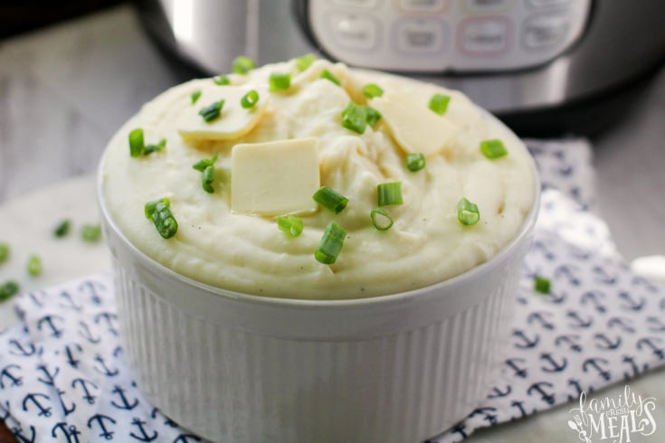 Best Instant Pot Mashed Potatoes - served in a white bowl, topped with chives and tabs of butter