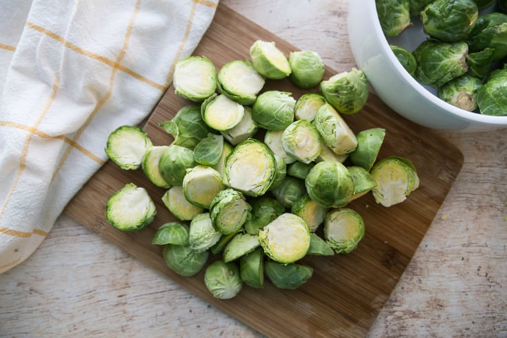 Crockpot Brussel Sprouts - fresh Brussels sprouts cut in half on a cutting board