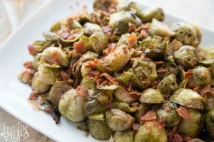 Cooked Brussels Sprouts sprinkled with bacon, served on a white plate