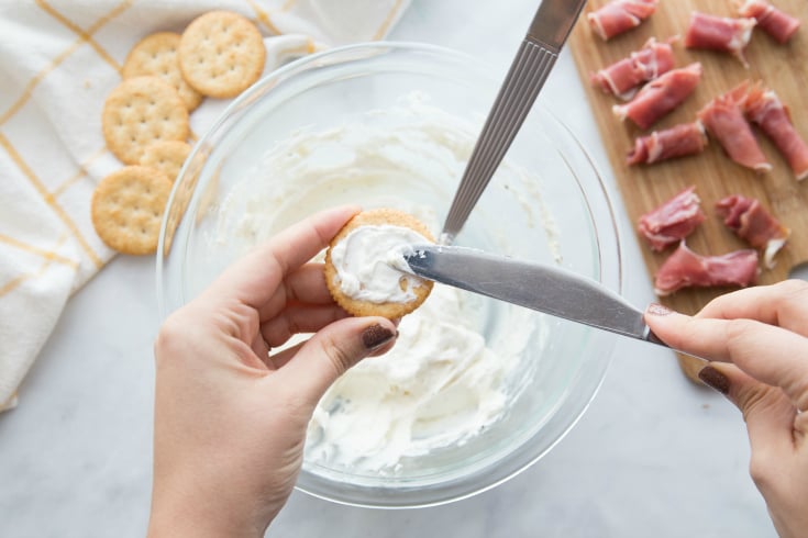 Easy Creamy Prosciutto Cracker Appetizer - spreading creamy mixture on a cracker