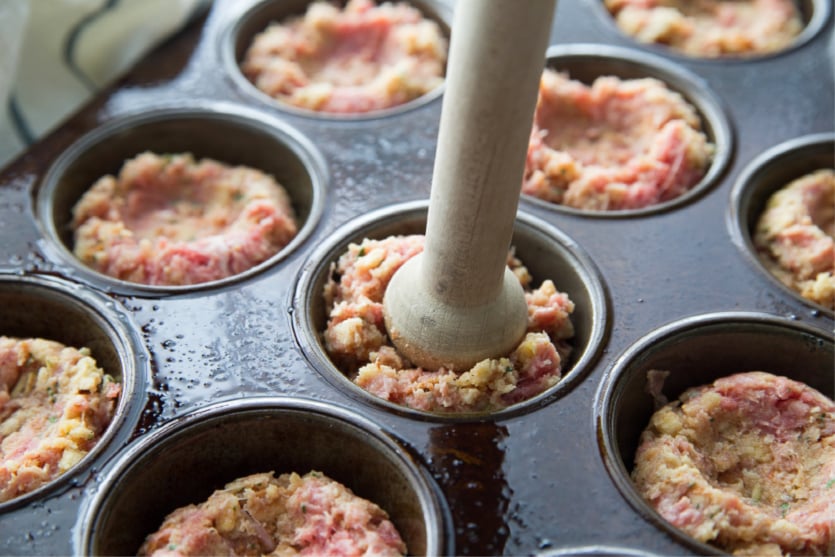 Mini Meatloaf Cupcakes - ground beef mixture in muffin tins, pushing in the middles of the mini meatloaf