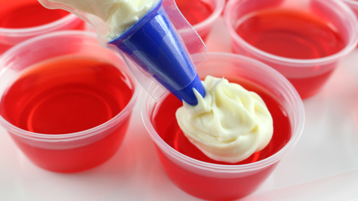 Santa Hat Holiday Jello Shots - Topping prepared jello shots with vanilla frosting