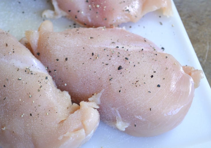 Seasoning chicken on a cutting board