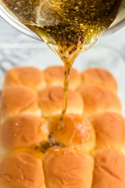 Cheesy Guinness Beef Sliders - pouring butter beer sauce over buns - Family Fresh Meals