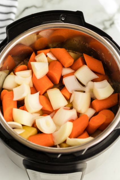 Instant Pot Pot Roast Dinner - onions, carrots and potatoes placed in instant pot - Family Fresh Meals