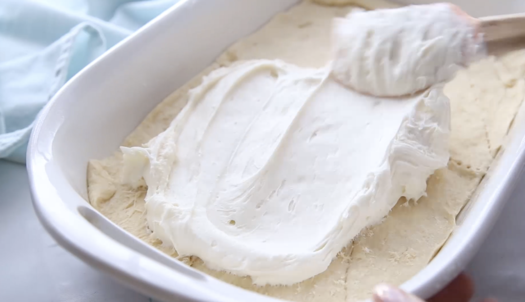 Churro Cheesecake Bars - Spreading cream cheese mixture on dough