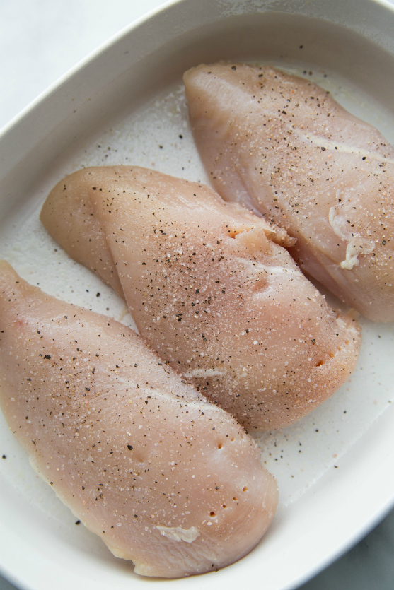 Creamy Fiesta Chicken Bake - Raw chicken seasoned in a baking pan - Family Fresh Meals