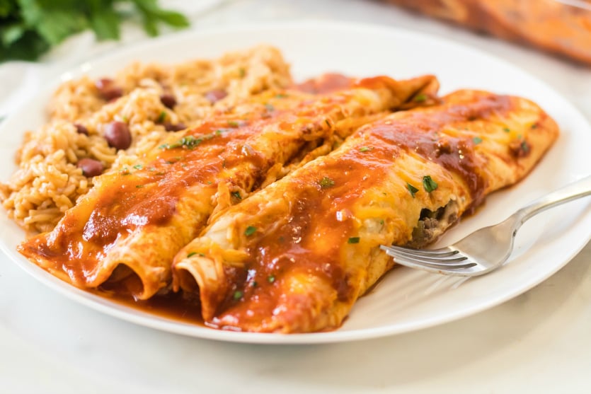 Easy Beef Enchiladas - Served on a white plate with rice - Family Fresh Meals