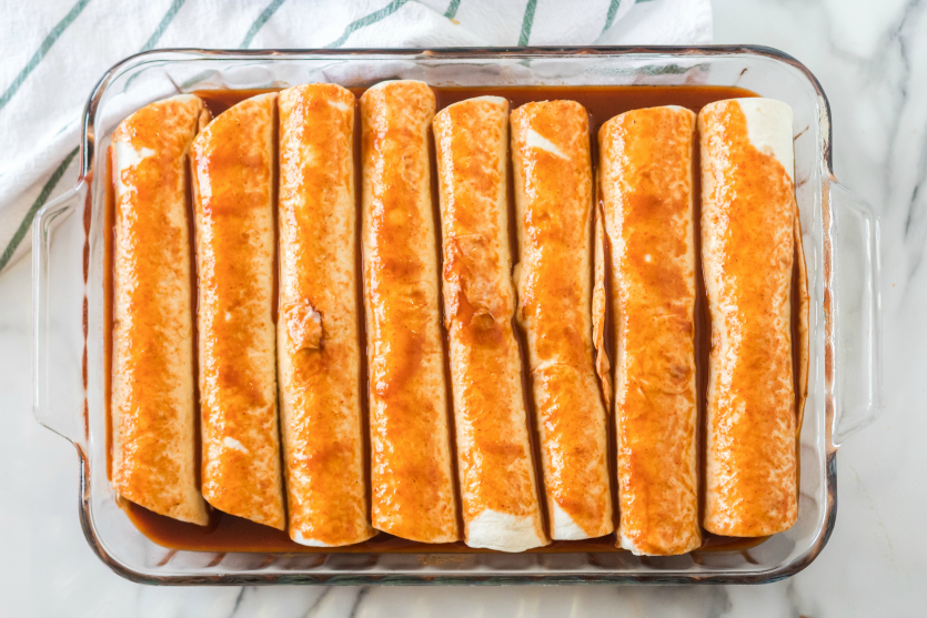 Easy Beef Enchiladas - rolled up tortillas in baking dish and topped with enchilada sauce - Family Fresh Meals