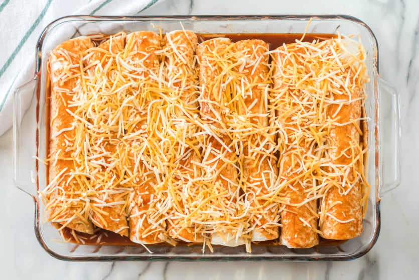 Easy Beef Enchiladas - rolled up tortillas in baking dish and topped with enchilada sauce and shredded cheese - Family Fresh Meals