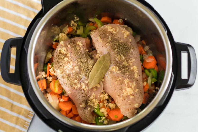 Instant Pot Chicken Noodle Soup - raw chicken, garlic and seasonings added into pressure cooker