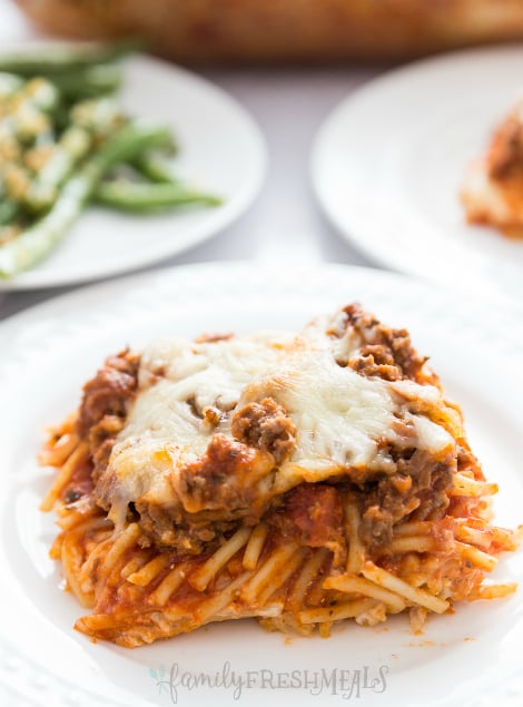 Million Dollar Baked Spaghetti - spaghetti bake served on a white plate and topped with cheese