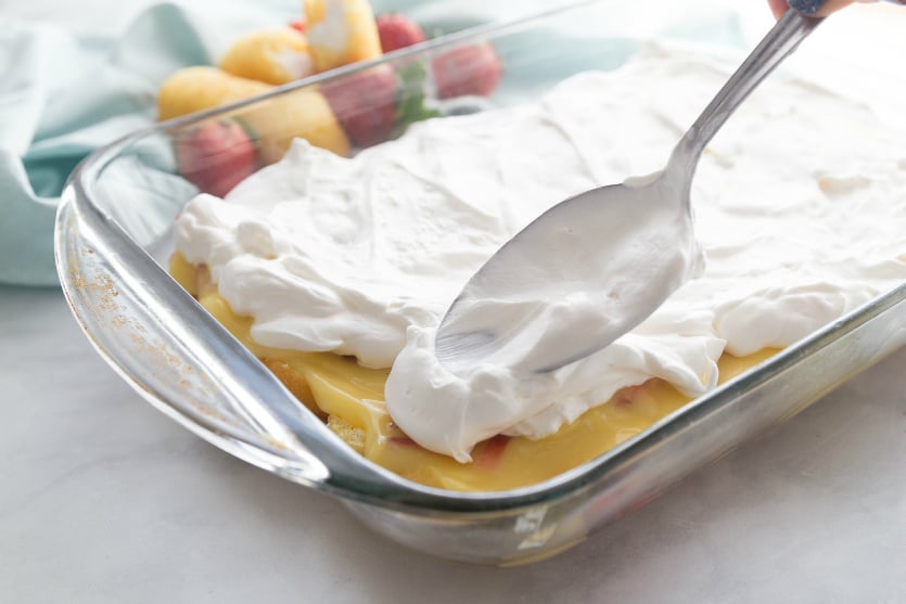 No Bake Strawberry Twinkie Cake - spreading whipped cream on top of pudding mixture