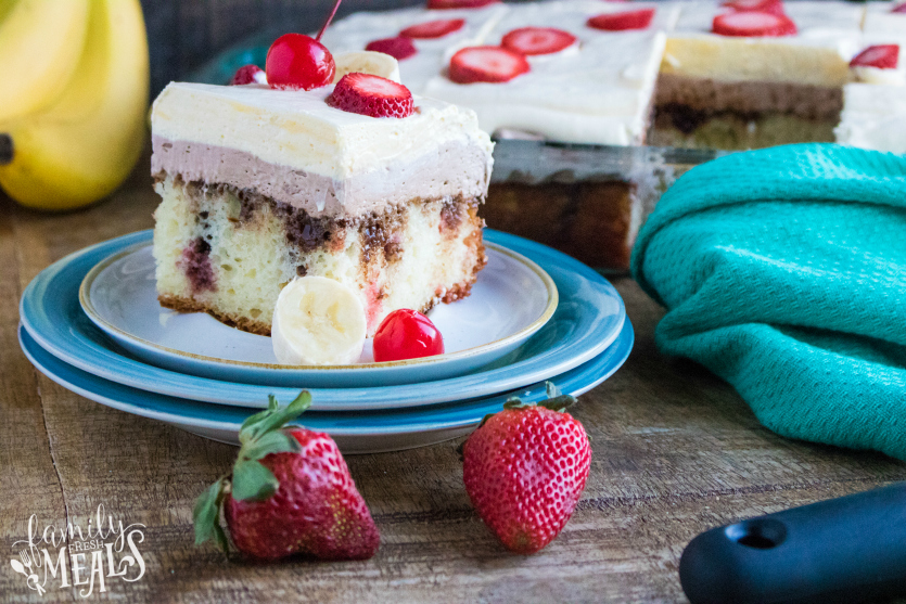 Banana Split Poke Cake - slice of cake served on a plate and topped with banana and strawberry slices