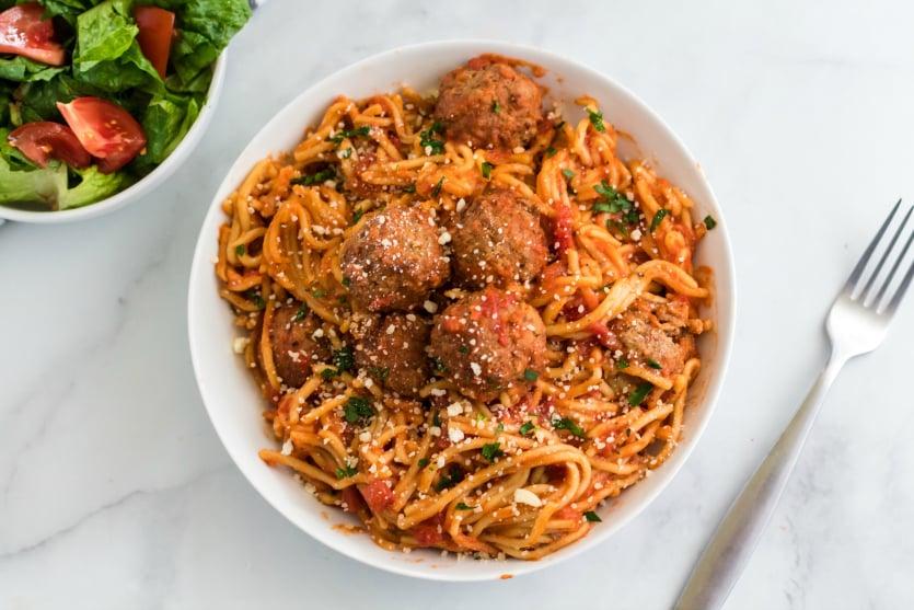 Crockpot Spaghetti and Meatballs - Served in a white bowl and topped with parmesan cheese