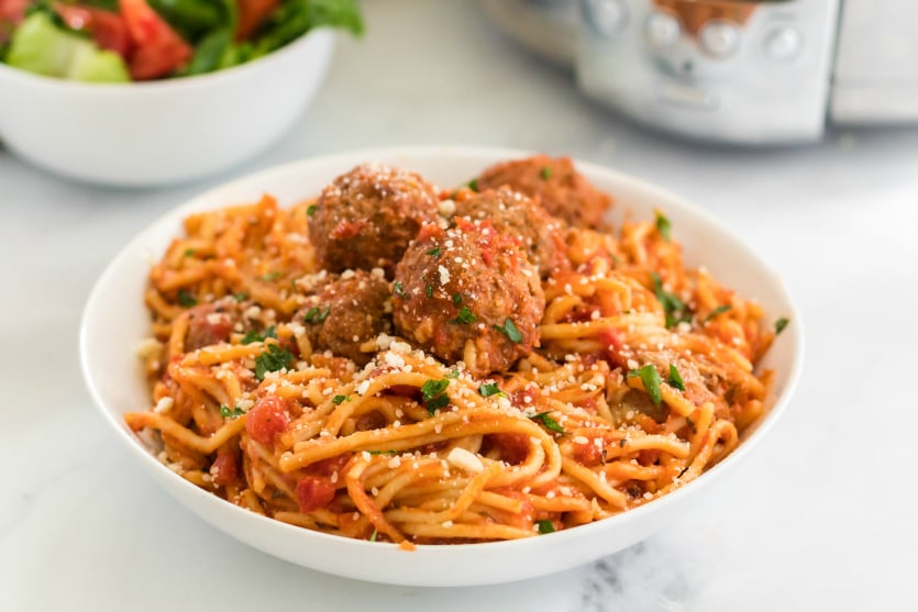 Crockpot Spaghetti and Meatballs recipe served in a white bowl with a side salad