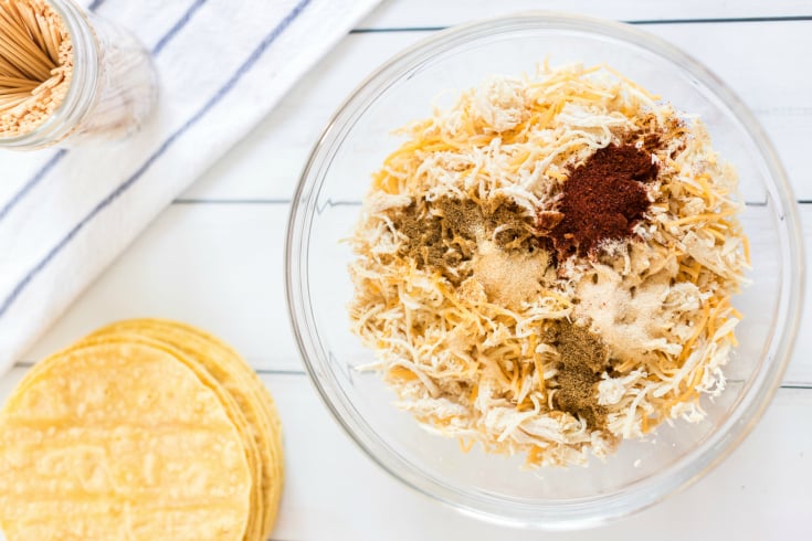 Easy Chicken Taquitos - shredded chicken, cheese with seasoning in a glass bowl