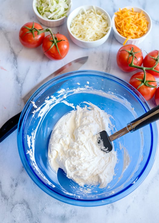 Easy Fiesta Taco Pizza - Mixing cream mixture in a blue bowl