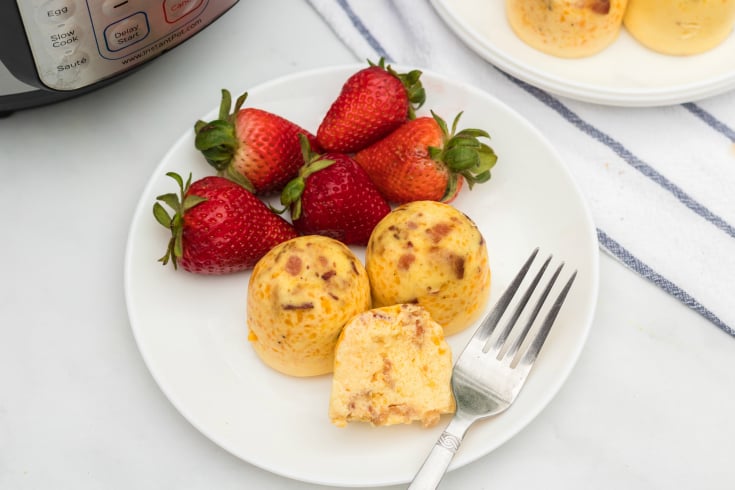Instant Pot Bacon Cheddar Egg Bites - Bacon cheddar egg bites on a white plate with strawberries