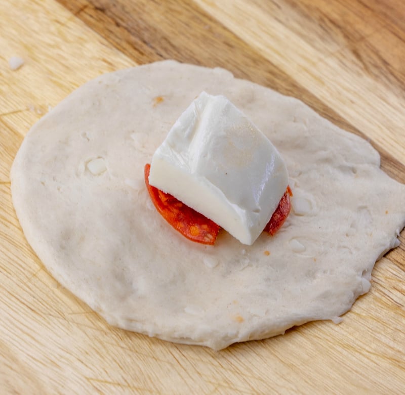 Cheesy Pizza Bombs - small round piece of dough with cheese and pepperoni on top