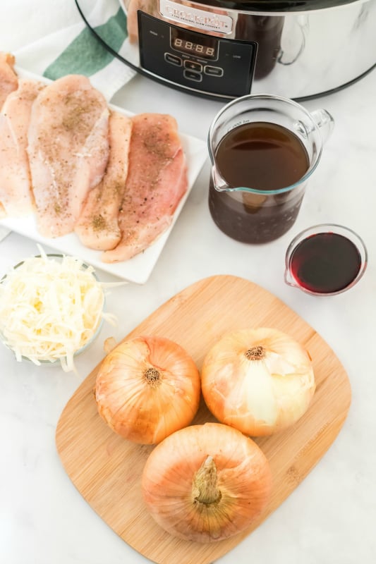 Crockpot French Onion Chicken - ingredients on table - chicken breasts, broth, wine, onions and shredded cheese