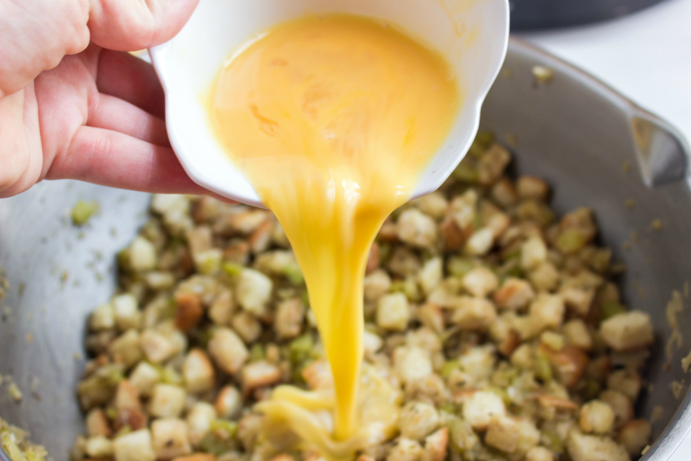 Easy Crockpot Stuffing - pouring beaten eggs in to stuffing mixture