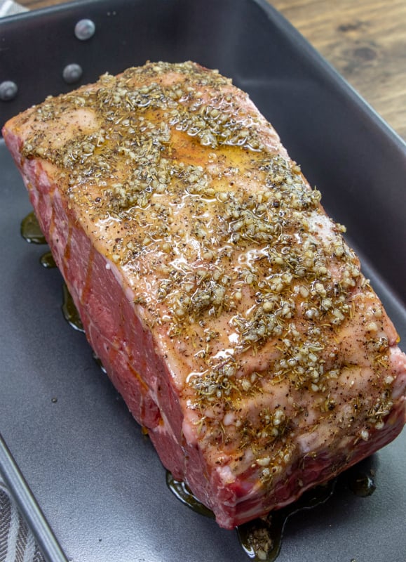 The Best Prime Rib Recipe - beef in baking pan with seasoning and oil brushed on top