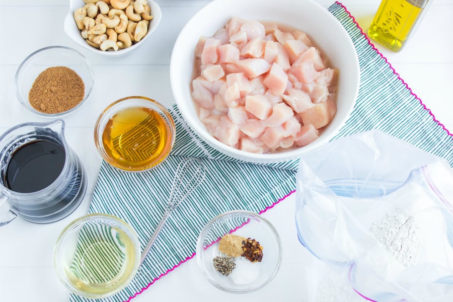 Crockpot Cashew Chicken - Ingredients in mixing bowls. Chicken, flour, seasoning, honey, brown sugar, soy sauce, oil