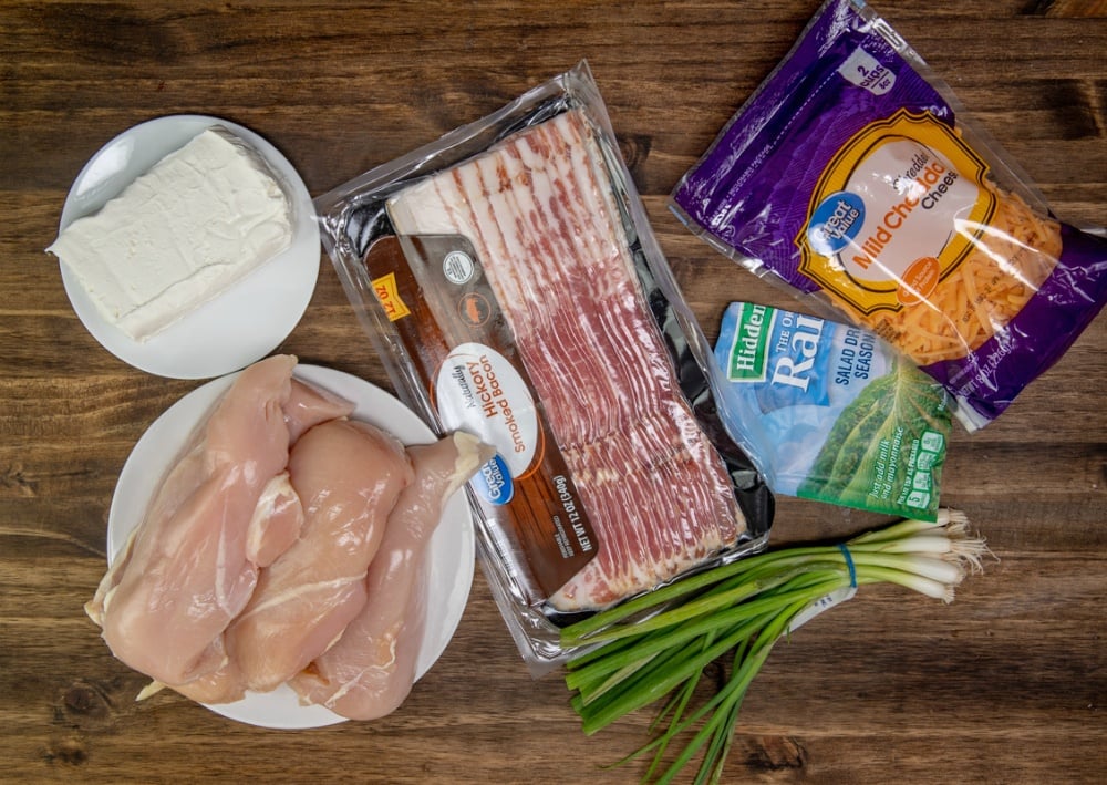 Creamy Crockpot Crack Chicken - ingredients on table. chicken, cream cheese, bacon, ranch, green onions cheddar