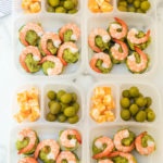 Top down photo of 4 easy lunchboxes with Shrimp Avocado, guacamole, olives and cheese cubes