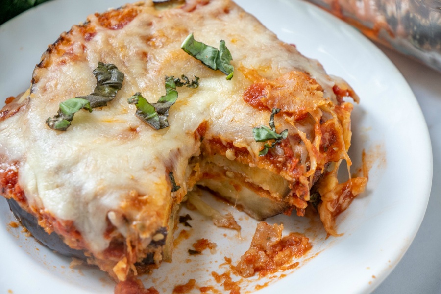 Sliced of the casserole served on a white plate and topped with basil